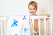 child in crib with butterfly swaddle hanging 