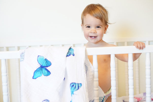 child in crib with butterfly swaddle hanging 