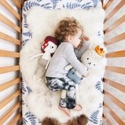 blue crib sheet with sheep skin on top 