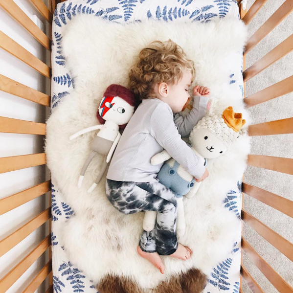 blue crib sheet with sheep skin on top 