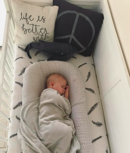 baby sleeping on side on top of crib sheet fitted